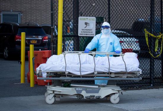 A medical worker transfers the body of a victim who died of COVID-19 at a hospital in New York, the United States, April 6, 2020. (Photo by Michael Nagle/Xinhua)