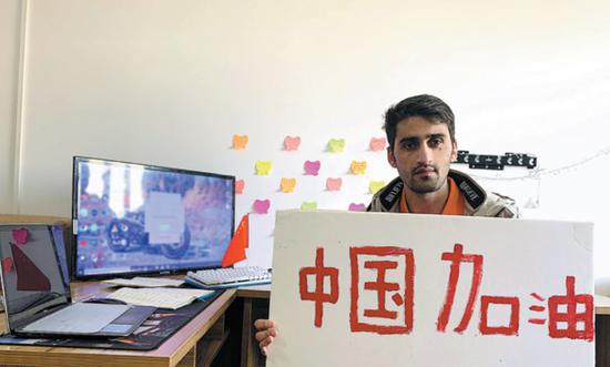 Ullah Inam, a Pakistani student at Henan University of Technology, holds a sign with the slogan 