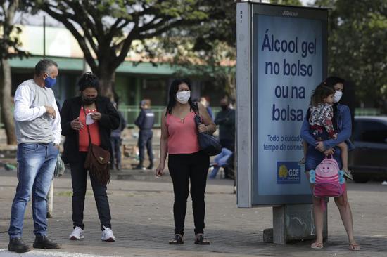 People wearing face masks wait for bus in Brasilia, Brazil, May 25, 2020. (Photo by Lucio Tavora/Xinhua)