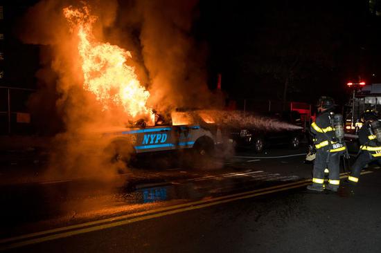 Firefighters put out a fire on a SUV of New York police department during a protest over the death of George Floyd in the Brooklyn borough of New York, the United States, May 30, 2020. (Photo by Michael Nagle/Xinhua)