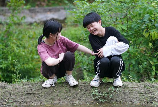 Luo Meiwei (L) and her brother Luo Chenghui have fun in a field in Shangyuan Village, Ruijin City of east China's Jiangxi Province, May 7, 2020. (Xinhua/Wan Xiang)