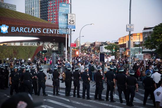 Police officers stand guard during a protest over the death of George Floyd in the Brooklyn borough of New York, the United States, May 31, 2020. (Photo by Michael Nagle/Xinhua)