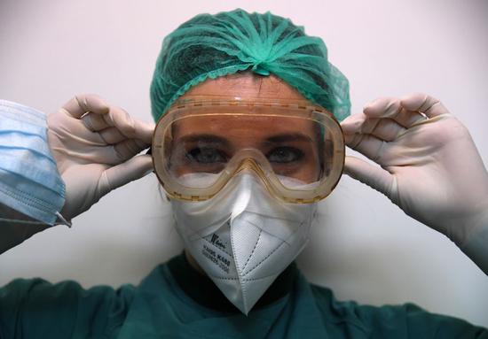 A nurse puts on protective equipment before entering the COVID-19 department at Santo Spirito Hospital in Rome, Italy, April 12, 2020. (Photo by Alberto Lingria/Xinhua)