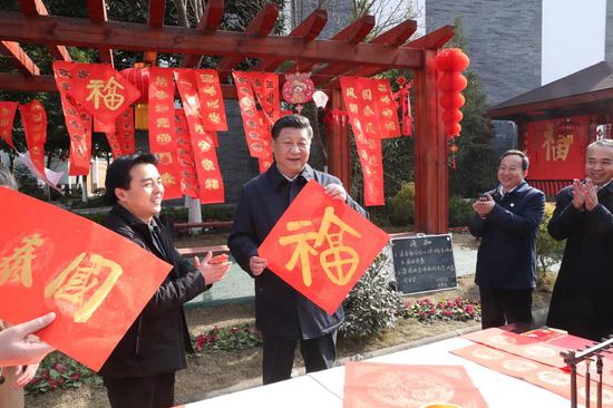 Chinese President Xi Jinping (2nd L), also general secretary of the Communist Party of China Central Committee and chairman of the Central Military Commission, shows a Chinese character "Fu", which means good luck, to extend the Spring Festival greetings in Zhanqi Village of Pidu District in Chengdu, southwest China's Sichuan Province, Feb. 12, 2018. (Xinhua/Xie Huanchi)