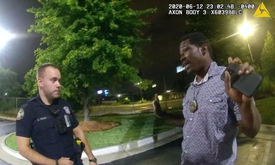 This screengrab taken from body camera video shows Garrett Rolfe (L), then the Atlanta police officer, listening to the 27-year-old African American Rayshard Brooks in the moments before Brooks' killing on June 12, 2020 in the U.S. city of Atlanta in Georgia State. (Photo credit: Atlanta Police Department)