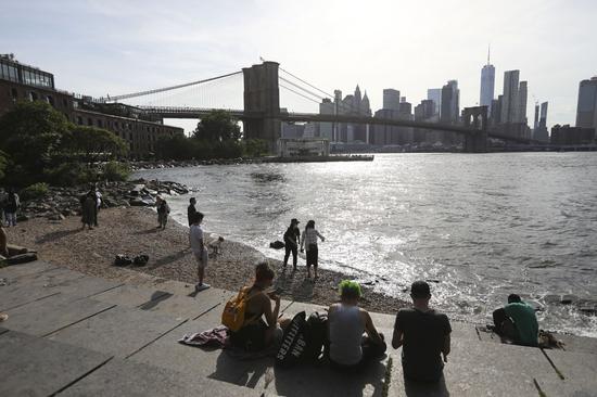 People enjoy sunshine at a park near Brooklyn Bridge in New York, the United States, June 15, 2020. (Xinhua/Wang Ying)