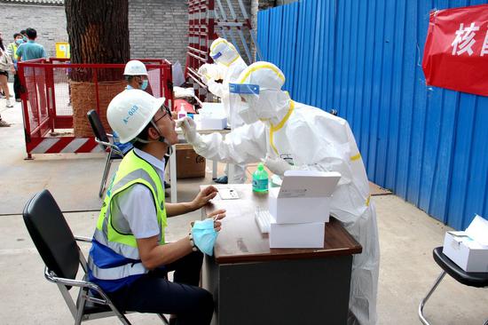 Medical workers collect throat swabs from construction workers at a construction site in Dongcheng District of Beijing, capital of China, June 17, 2020. (Photo by Ke Yuqian/Xinhua)