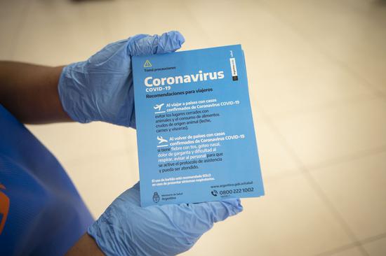 An employee from the Health Ministry shows a brochure for international arrival passengers at the Ministro Pistarini International Airport in Ezeiza, Argentina, March 12, 2020. (Xinhua/Martin Zabala)