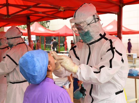 
A medical worker (R) collects a throat swab from a woman at a nucleic acid testing site in Peking University Hospital, Beijing, capital of China, June 24, 2020. (Xinhua/Ren Chao)