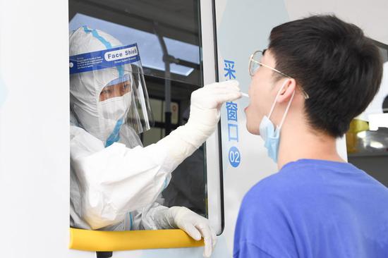 A medical staff member takes a throat swab sample from a man at a newly-adopted mobile testing vehicle in Xicheng District of Beijing, capital of China, June 28, 2020. (Xinhua/Ju Huanzong)