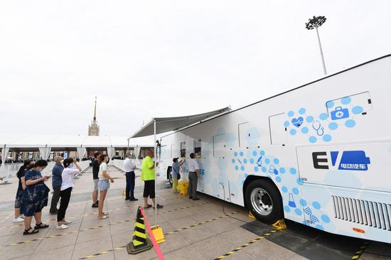 Medical staff members take throat swab samples from people at a newly-adopted mobile testing vehicle in Xicheng District of Beijing, capital of China, June 28, 2020. (Xinhua/Ju Huanzong)