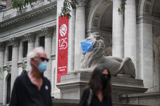 A marble lion is seen with a face mask in front of the New York Pubulic Library on the Fifth Avenue in New York, the United States, July 8, 2020. (Xinhua/Wang Ying)