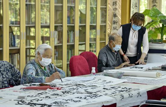 Elderly people practice calligraphy accompanied by a staff member at the Sijiqing nursing home in Haidian District of Beijing, capital of China, May 10, 2020. (Xinhua/Li Xin)