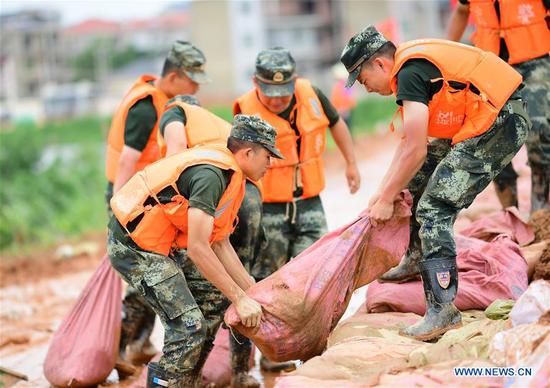 Armed policemen move sand bags for dyke reinforcement in Poyang County, east China's Jiangxi Province, July 12, 2020.  (Photo by Cao Xianxun/Xinhua)