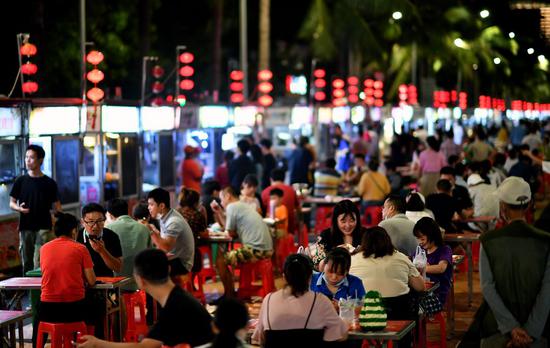 People enjoy snacks at a night market in Haikou, capital of south China's Hainan Province, March 26, 2020. (Xinhua/Guo Cheng)