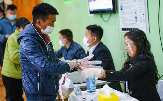 A voter receives disposable gloves at a polling station in Ulan Bator, Mongolia, June 24, 2020. (Photo by Chadraabal/Xinhua)