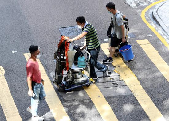Workers cross a street with equipment in Hong Kong, south China, July 13, 2020. (Xinhua/Li Gang)