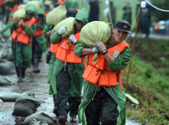 Members of the armed police carry sandbags to reinforce a section of the levee in Baimao Town of Wuhu, east China's Anhui Province, July 16, 2020. (Xinhua/Zhou Mu)