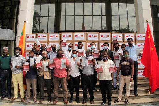 Officials and local three-wheel drivers pose for a photo at the donation ceremony in Colombo, Sri Lanka, July 29, 2020. (Xinhua/Tang Lu)