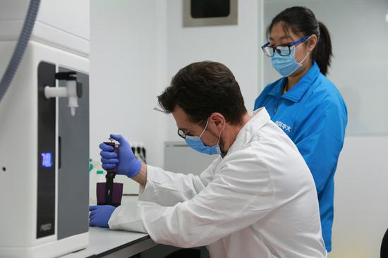 A Chinese expert (R) from Chinese biotech company BGI Group provides training to a Serbian expert at the Fire Eye laboratory in Belgrade, Serbia, April 20, 2020. (Xinhua File/Shi Zhongyu)