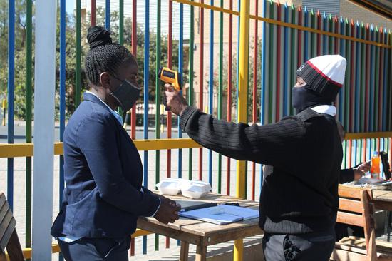A security officer checks the temperature of a local at an entrance in Windhoek, capital of Namibia, June 18, 2020. (Xinhua/Ndalimpinga Iita)