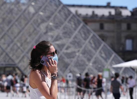 A woman wearing a face mask walks past the Pyramid of Louvre Museum in Paris, France, Aug. 7, 2020.(Xinhua/Gao Jing)