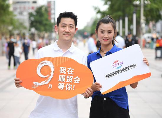 Performers show signs of the China International Fair for Trade in Services in the Wangfujing pedestrian street in Beijing, capital of China, Aug. 4, 2020. (Xinhua/Ren Chao)