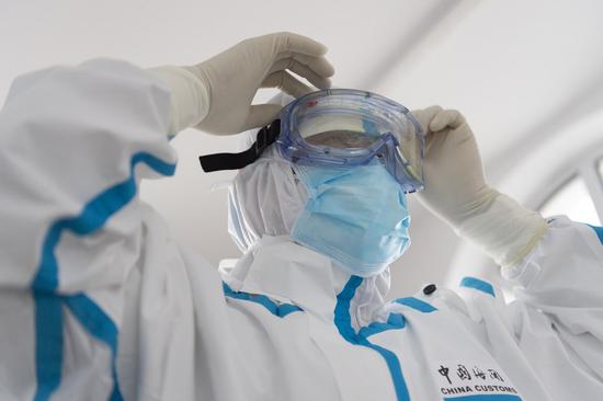 A member of staff puts on protective equipments at the port of Fuyuan in northeast China's Heilongjiang Province, Aug. 13, 2020. The port of Fuyuan, which mainly exports vegetables, fruits and engineering machinery and imports wood, soybeans and flour, has been carrying out strict measures against COVID-19, making sure that all personnel are healthy and all goods are disinfected while maintaining a smooth transportation process. (Xinhua/Xie Jianfei)