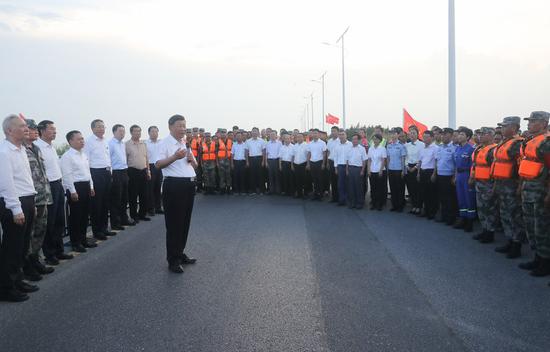 Chinese President Xi Jinping, also general secretary of the Communist Party of China Central Committee and chairman of the Central Military Commission, expresses his regards to those fighting the floods at the front line, including military personnel from the People's Liberation Army (PLA) and the People's Armed Police Force, at a section of a dam in Feidong County of Hefei, capital of east China's Anhui Province, Aug. 19, 2020. (Xinhua/Ju Peng)