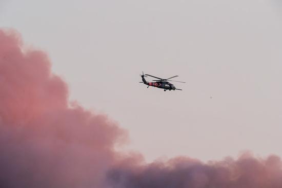 Photo taken on Aug. 19, 2020 at the Windy Hill Open Space Preserve of San Mateo County shows a helicopter flying over the dense smoke of wildfires in San Francisco Bay Area, California, the United States. (Photo by Dong Xudong/Xinhua)