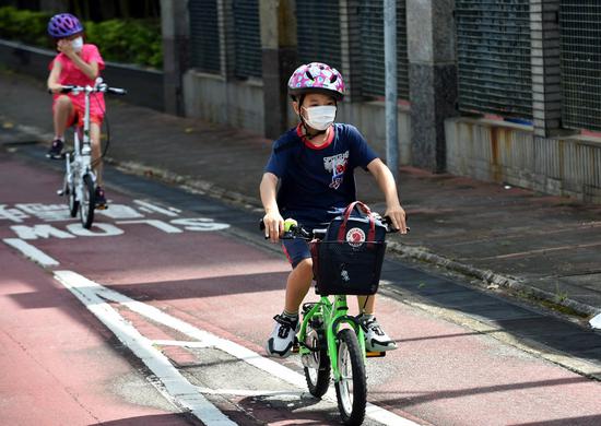Children ride bicycles on a road in Hong Kong, south China, Aug. 10, 2020. (Xinhua/Lo Ping Fai)