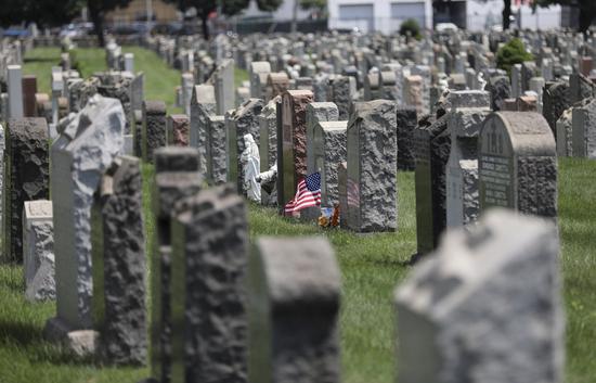 A U.S. national flag and flowers are seen at a cemetery in New York, the United States, July 29, 2020. (Xinhua/Wang Ying)