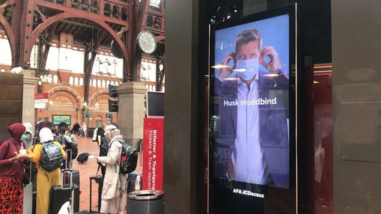 An information screen in the Central Station of Copenhagen shows Danish health authorities' promotions on wearing face-masks on public transports in Copenhagen, Denmark, Aug. 24, 2020. (Photo by Anders Kongshaug/Xinhua)