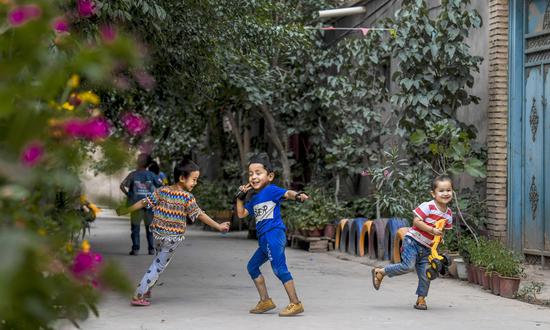 Children have fun in an alley at Qianjin Village in Kashgar, northwest China's Xinjiang Uygur Autonomous Region, Aug. 18, 2019. (Photo/Xinhua)