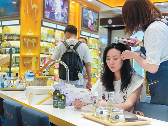 A customer experiences haircare service at a L'Occitane store in Shanghai in September. CHINA DAILY