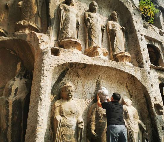 A staff member places 3D-printed Buddha's head at the Longmen Grottoes scenic area in Luoyang, central China's Henan Province, Sept. 23, 2020. (Photo provided to Xinhua)