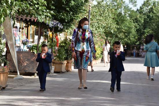 2020年5月24日，一名妇女和两个孩子参观了中国西北维吾尔自治区的喀什古城。（新华社/高寒）