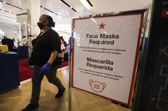 A woman wearing a face mask walks past a notice board with COVID-19 preventive instructions at a Macy's store in New York, the United States, on Oct. 16, 2020. (Xinhua/Wang Ying)