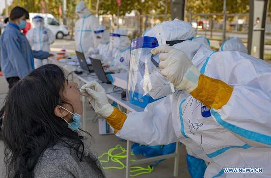 A medical worker stands by as people line up to have their samples collected for nucleic acid testing in Shufu County of Kashgar Prefecture, northwest China's Xinjiang Uygur Autonomous Region, Oct. 26, 2020. (Xinhua/Hu Huhu)