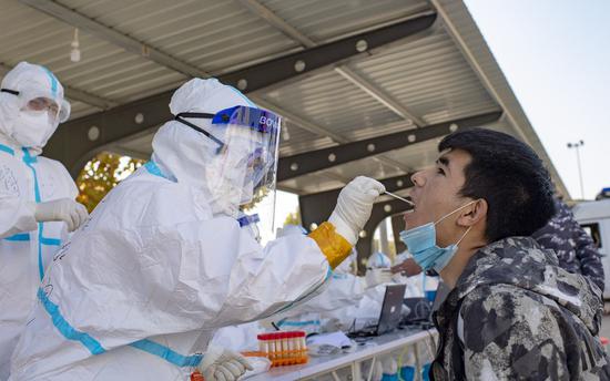 A medical worker collects a sample from a person for nucleic acid testing in Shufu County of Kashgar Prefecture, northwest China's Xinjiang Uygur Autonomous Region, Oct. 26, 2020. (Xinhua/Hu Huhu)