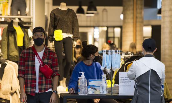 Personal protective equipment for customers are placed at the entrance of a clothing store in Toronto, Canada, on Oct. 27, 2020. (Photo by Zou Zheng/Xinhua)