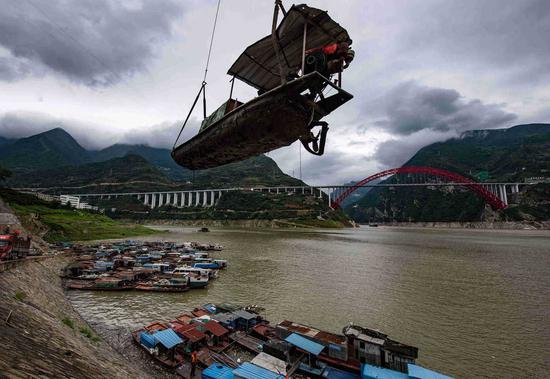 A fishing boat is hoisted ashore for dismantling in Yichang's Zigui county, Hubei province, on July 13 in preparation for a 10-year fishing ban on the Yangtze River. (Photo: Zheng Jiayu for China Daily)