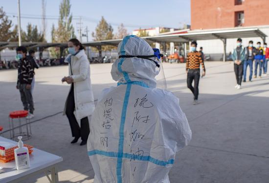 A medical worker stands by as people line up to have their samples collected for nucleic acid testing in Shufu County of Kashgar Prefecture, northwest China's Xinjiang Uygur Autonomous Region, Oct. 26, 2020. (Xinhua/Hu Huhu)