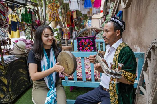 Local residents who are involved in the tourism business play music for tourists in the old town of Kashgar, northwest China's Xinjiang Uygur Autonomous Region. Photo: Xinhua