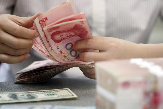 A worker counts Chinese currency renminbi at a bank in Linyi, East China's Shandong province. (Photo/Xinhua)