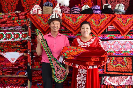 A couple display embroidery works at a handicraft making cooperative in Aketao County of northwest China's Xinjiang Uygur Autonomous Region, Sept. 20, 2020. (Xinhua/Gao Han)