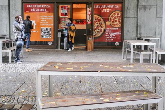 A customer leaves a pizza restaurant with take-away food in Berlin, capital of Germany, Nov. 2, 2020. (Xinhua/Shan Yuqi)