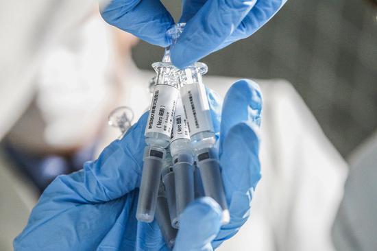 A staff member displays samples of the COVID-19 inactivated vaccine at Sinovac Biotech Ltd., in Beijing, capital of China, March 16, 2020. (Xinhua/Zhang Yuwei)