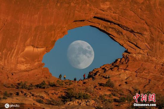 Full moon looking like giant eye in stunning rock arch photograph
