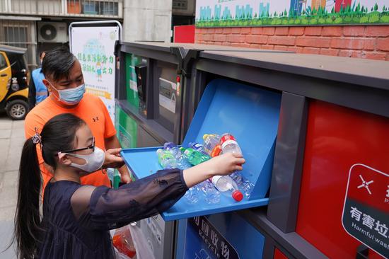 A child puts plastic bottles into the intelligent garbage bin of blue color at the Shaojiu residential community in Dongcheng District of Beijing, capital of China, May 17, 2020. (Xinhua/Ju Huanzong)
